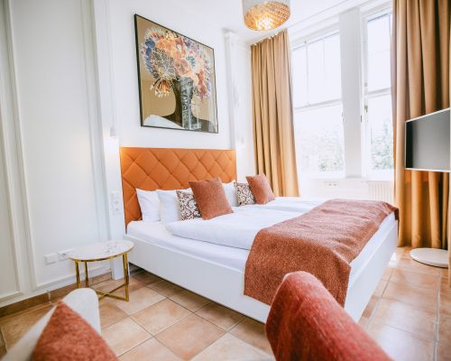 Orangenes Doppelzimmer mit großem Fenster und modernen Gemälde an der Wand