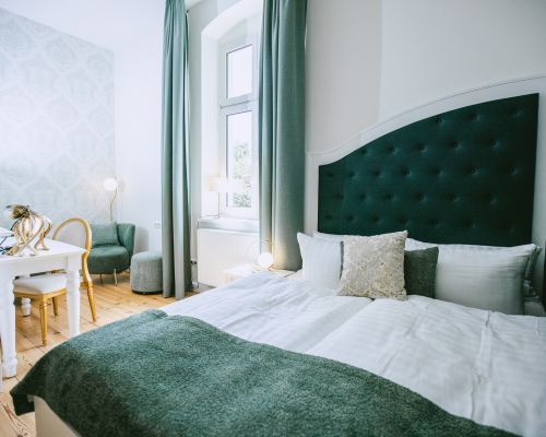 Das grüne, stilvoll eingerichtete Doppelzimmer mit einem klassichen Doppelbett